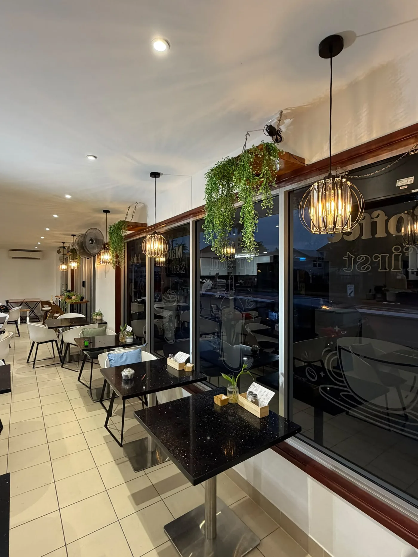 Cafe dining area with newly installed pendant lighting and downlights at dusk - Cairns City Electrics, Cairns