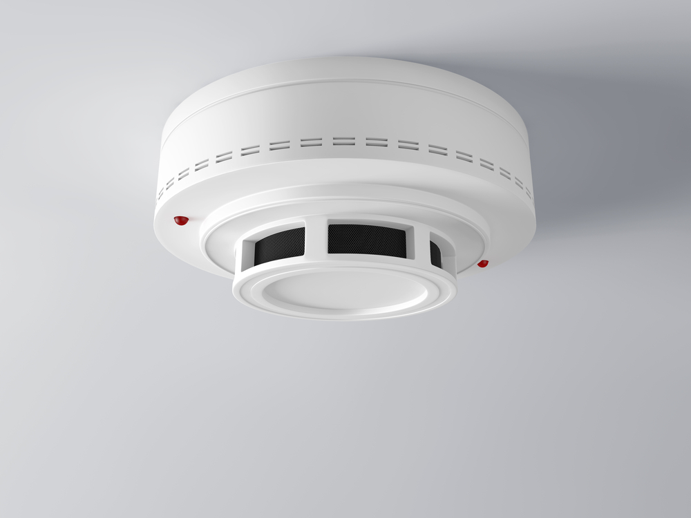 White photoelectric smoke alarm installed on a ceiling with indicator lights showing - Cairns City Electrics, Cairns